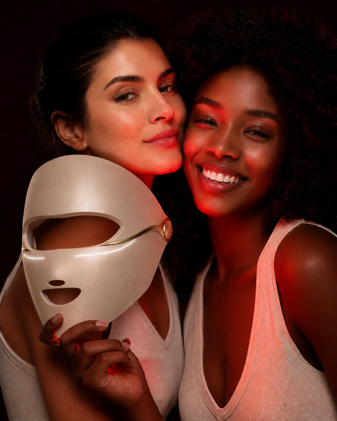 Campaña de Wellogic: dos mujeres sostienen el prototipo de máscara M10 en color champaña, con el logotipo original de Wellogic en la zona de la mejilla.